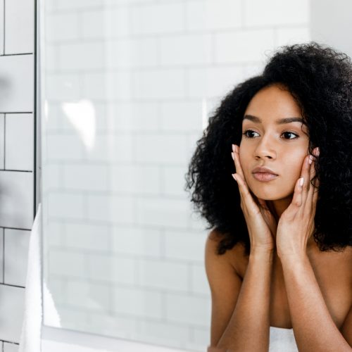 Mixed race woman massaging her face and looking at a mirror Mixed race woman massaging her face and looking at a mirror